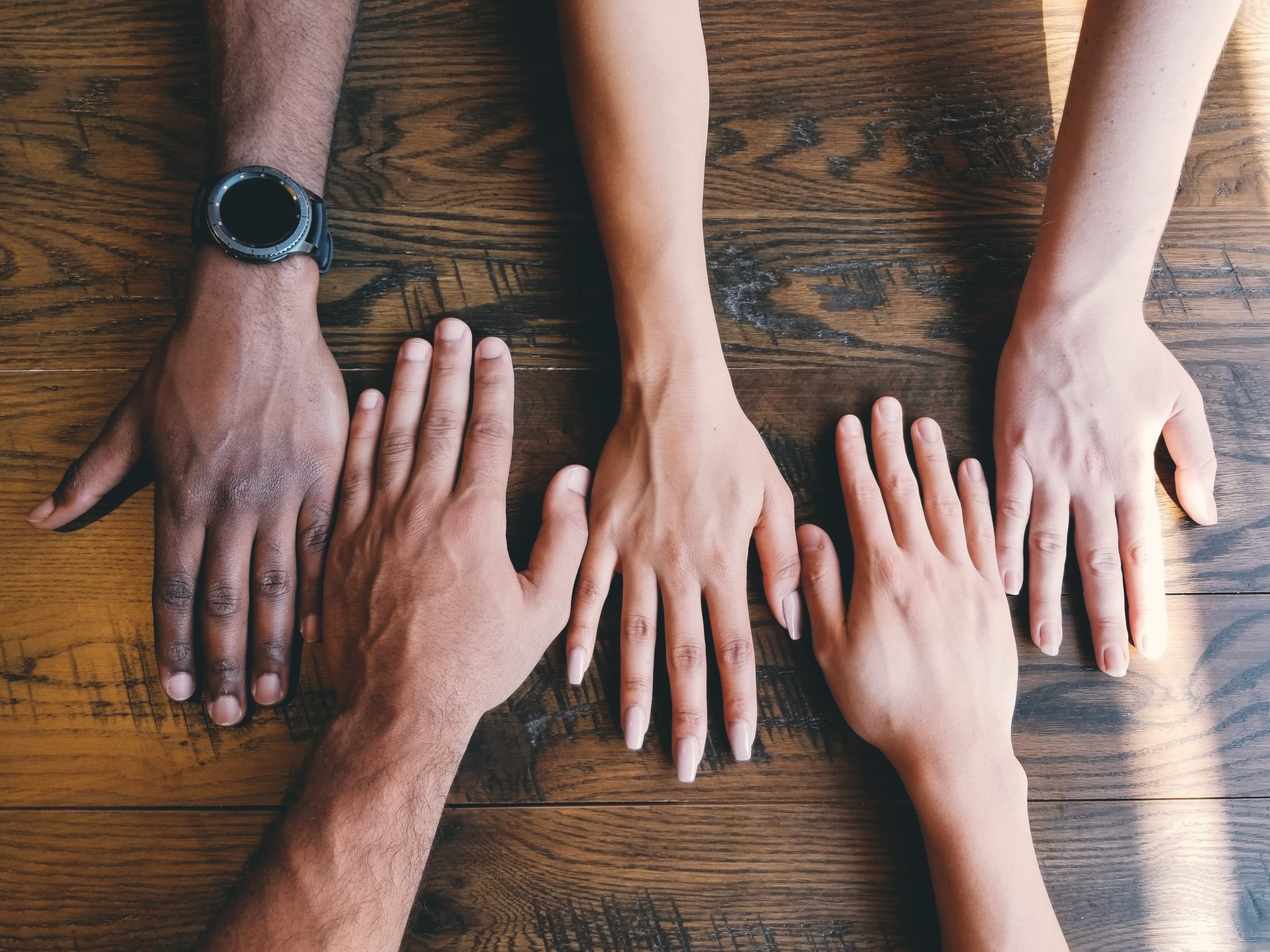 colored hands on a wooden table teamwork