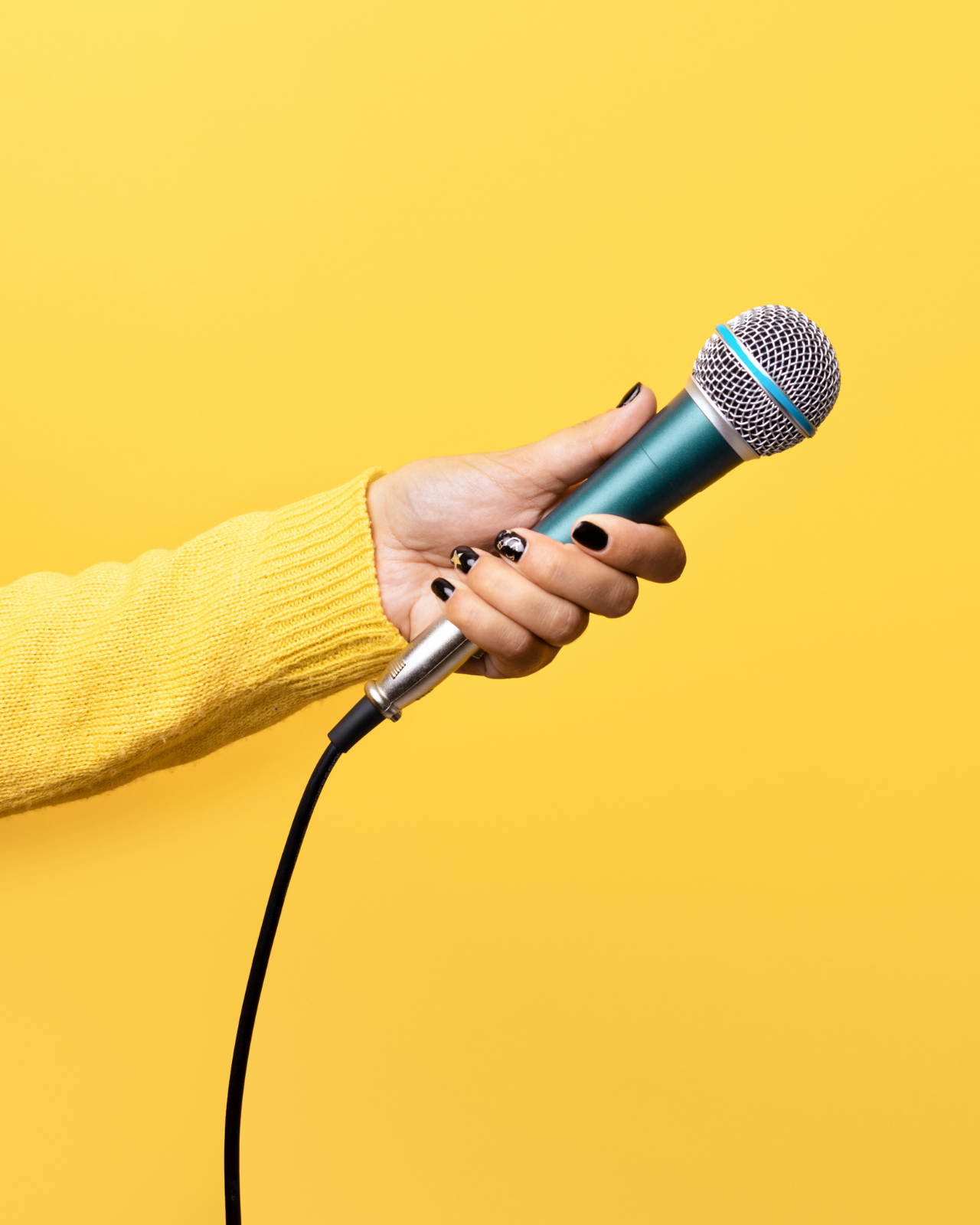 Hand holding microphone centered on yellow background